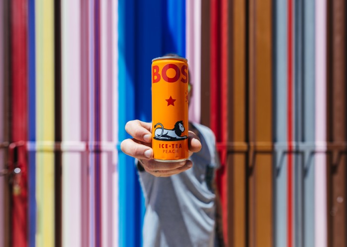 person holding a bos ice tea can